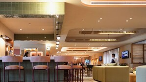 Un espace bar moderne avec des tabourets hauts, un comptoir et un coin salon comprenant un canapé et des fauteuils.