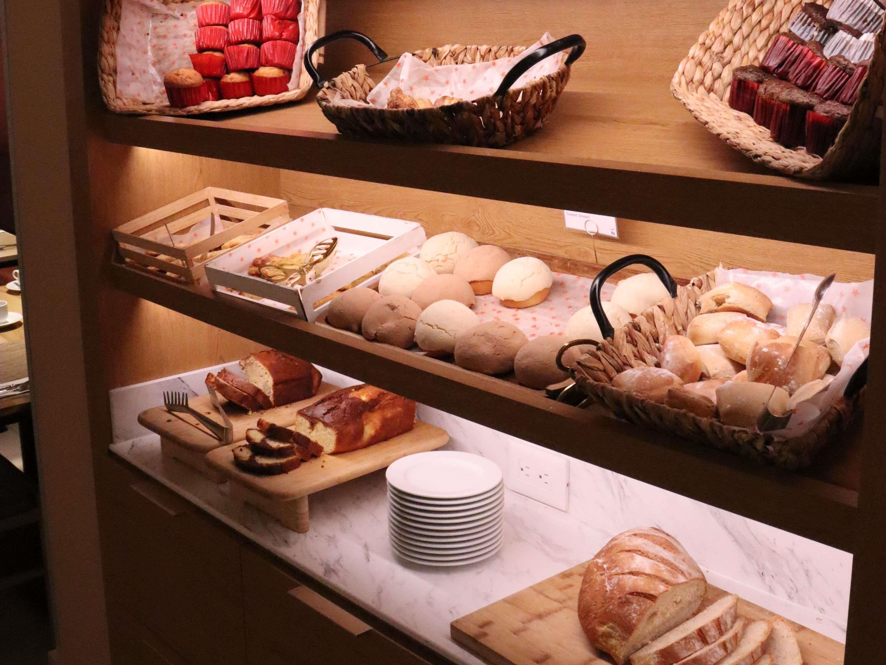 A bakery display with various baked goods including muffins, buns, and bread.