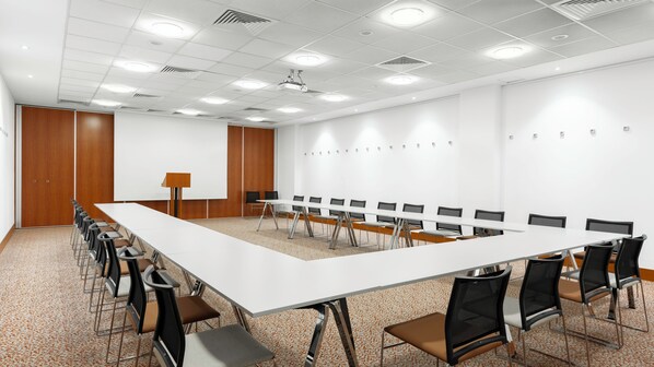 A conference room with a long table, chairs, a projector, and a whiteboard.