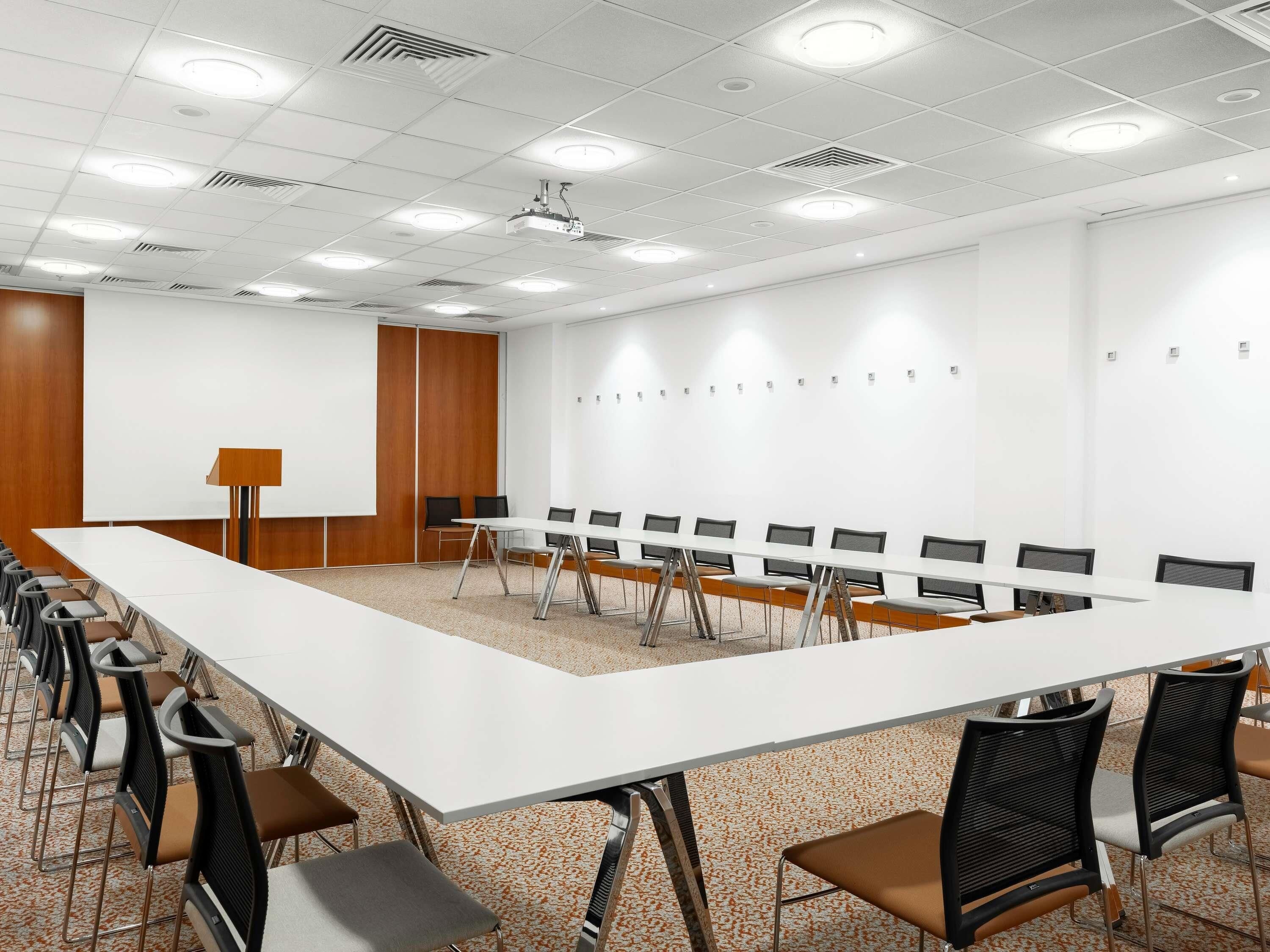 A conference room with a long table, chairs, a projector, and a whiteboard.