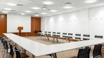A conference room with a long table, chairs, a projector, and a whiteboard.