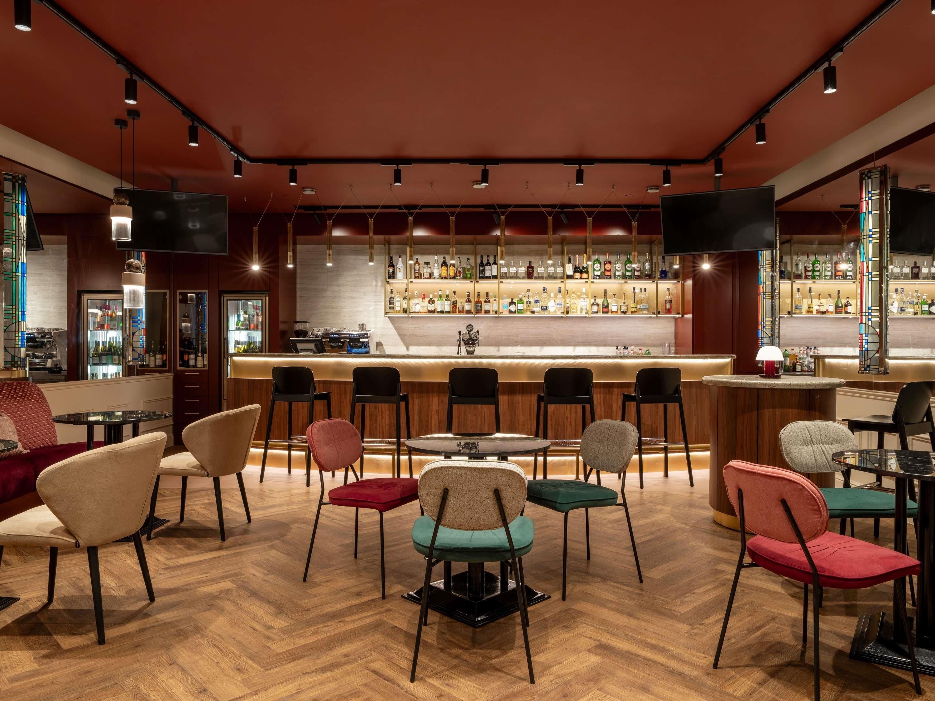 Zona de bar con diversas opciones de asientos, una barra y una variedad de botellas.