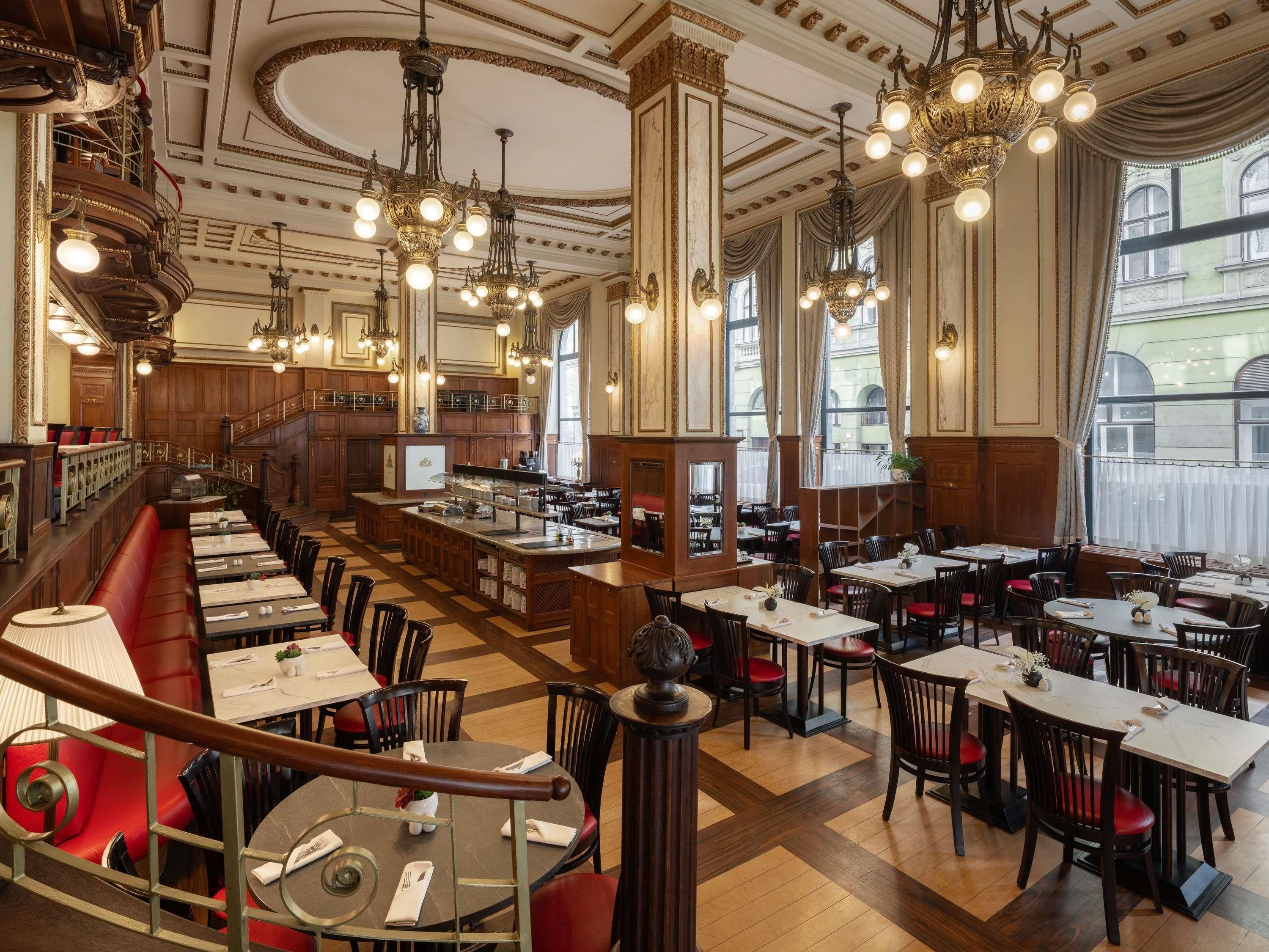 A spacious restaurant with multiple dining areas, a central bar, and ornate chandeliers.
