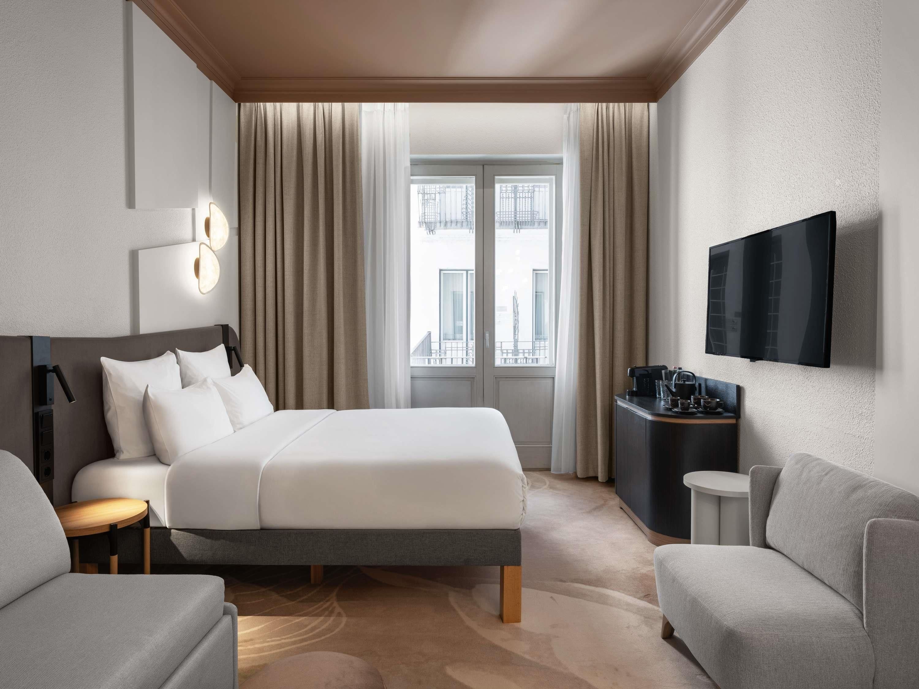 Una habitación de hotel con cama, televisión, escritorio y vistas a la ciudad.