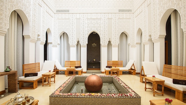 A luxurious lobby with ornate arches, a central fountain, and seating areas.
