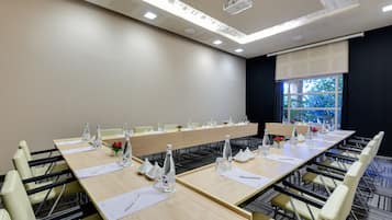 A conference room with a long table, chairs, water bottles, and a projector on the ceiling.
