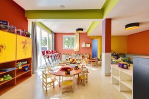 A brightly colored children's playroom with a large table, chairs, and shelves filled with toys. - Barcelo Palmeraie Oasis Resort (Marrakech)