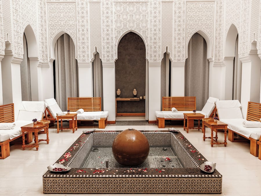 Ein luxuriöser Spa-Bereich mit einer großen, zentralen Fontäne, verschiedenen Sitzgelegenheiten und aufwendigen Wandgestaltungen.
