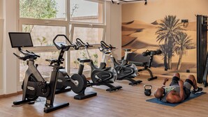 A gym with stationary bikes, a treadmill, and a wall mural.