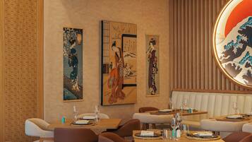 A restaurant interior with traditional artwork on the walls, wooden furniture, and a modern design aesthetic.