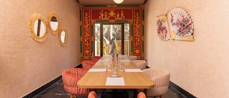 Uma sala de conferências com uma mesa comprida, várias cadeiras e elementos decorativos na parede.