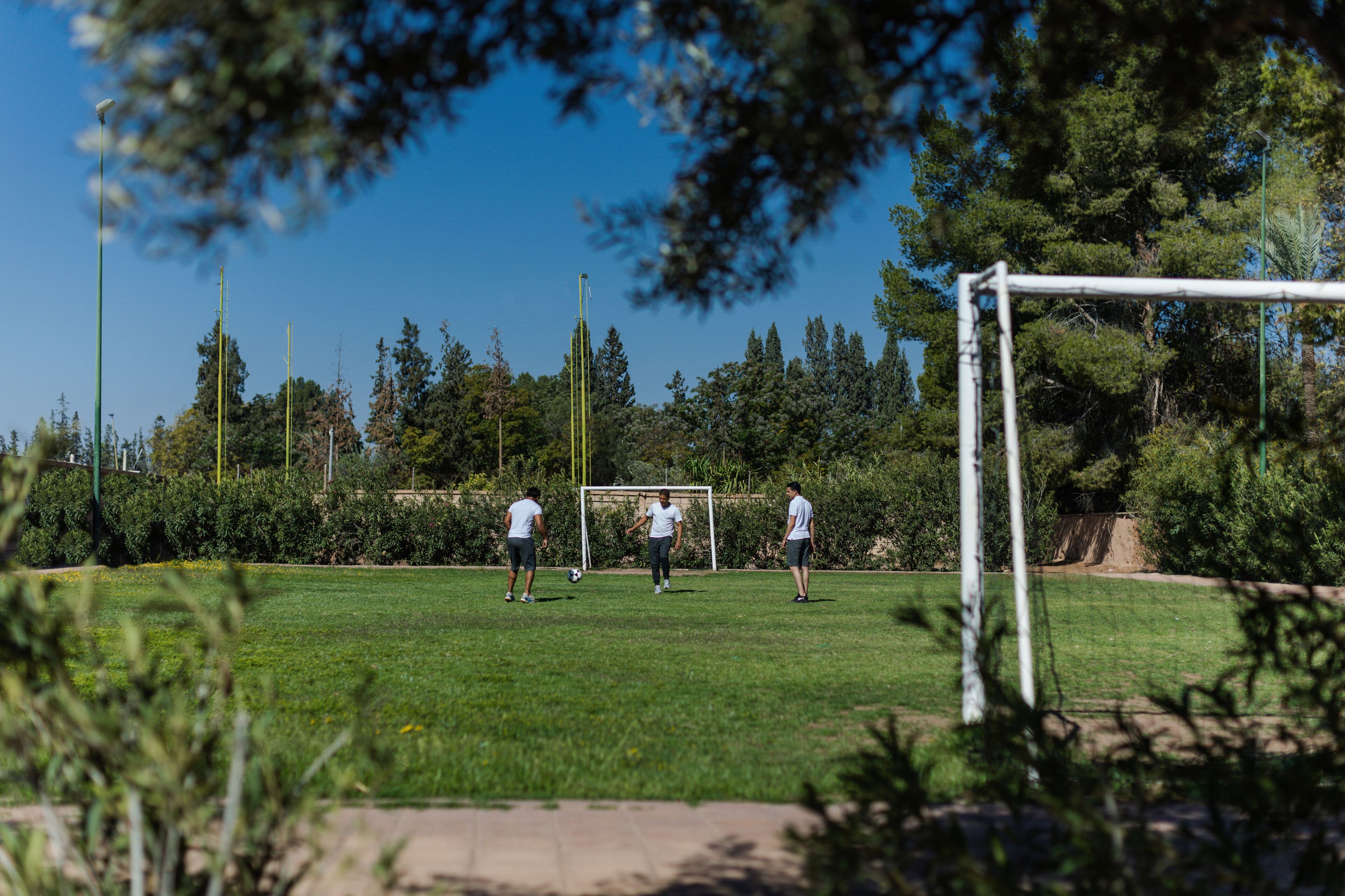 An outdoor soccer field with goalposts, surrounded by trees and greenery.