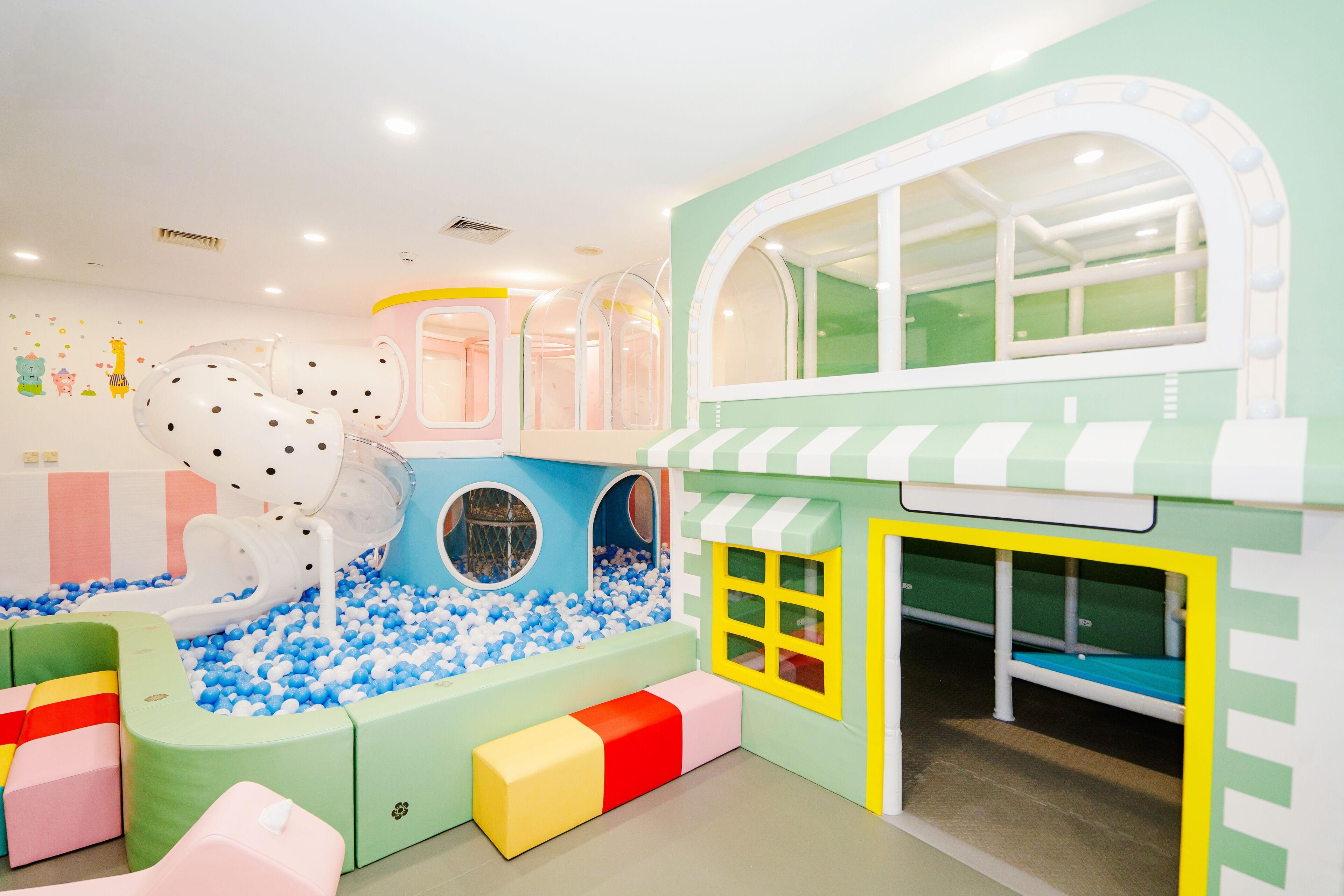A children's play area with a ball pit, play structures, and a small building with windows.