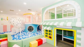 A children's play area with a ball pit, play structures, and a small building with windows.