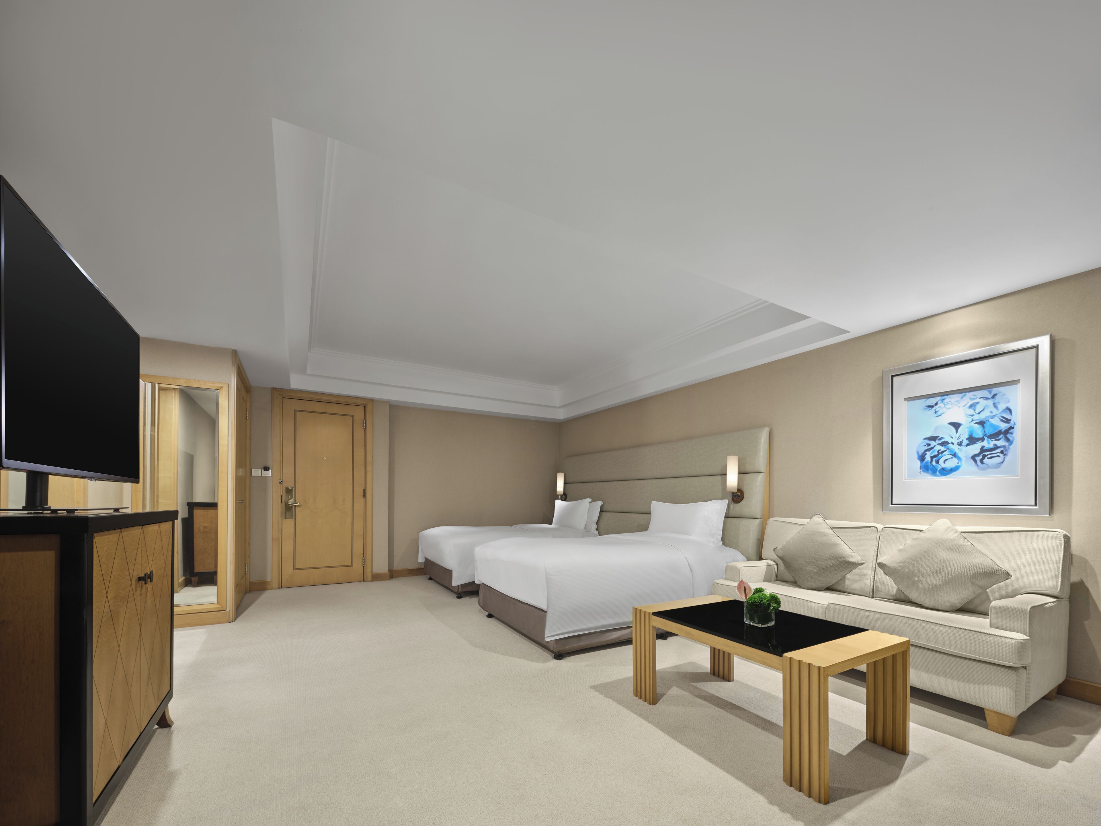 Une chambre d’hôtel avec un lit, un canapé, une télévision et un tableau au mur.