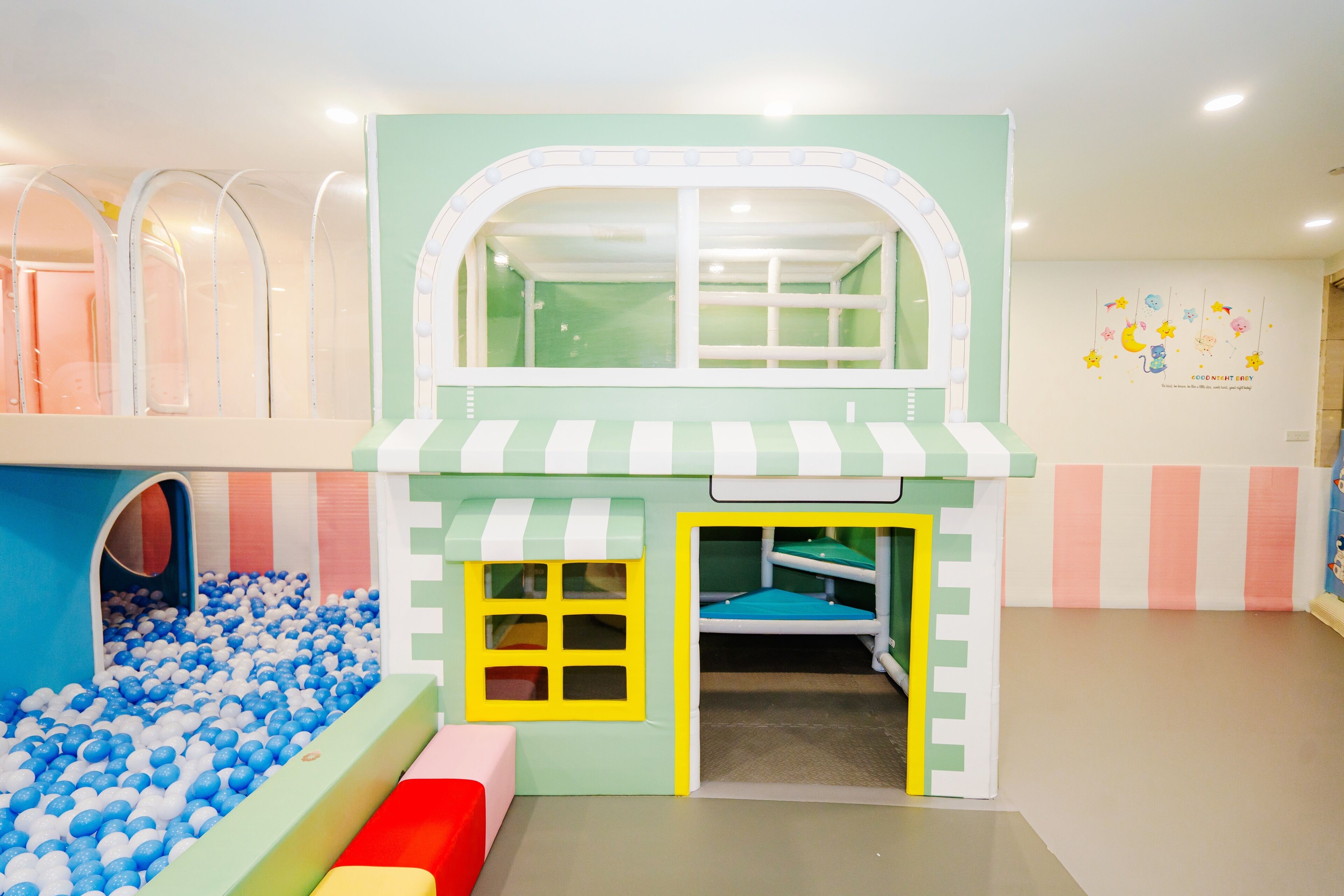 Zona infantil con piscina de pelotas, tobogán y casita.