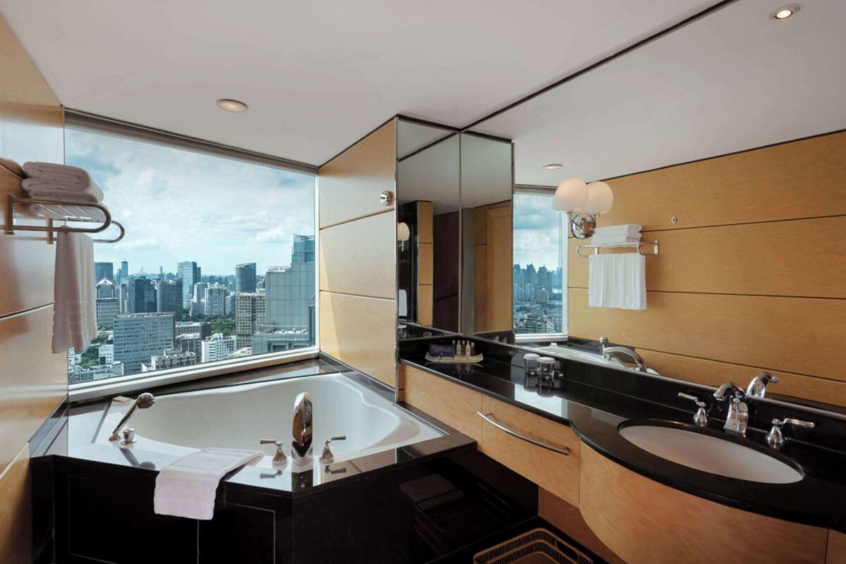 A modern bathroom with a large bathtub, two sinks, and a large mirror.