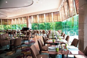 A spacious dining area with high ceilings, large windows, and a variety of seating arrangements. - DoubleTree by Hilton Hotel Shanghai - Pudong (Shanghai)
