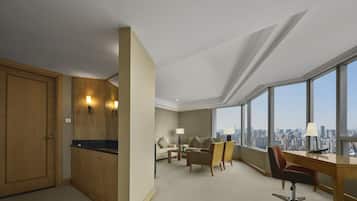 A hotel room with a city view, a desk, a chair, a sofa, and a wardrobe.