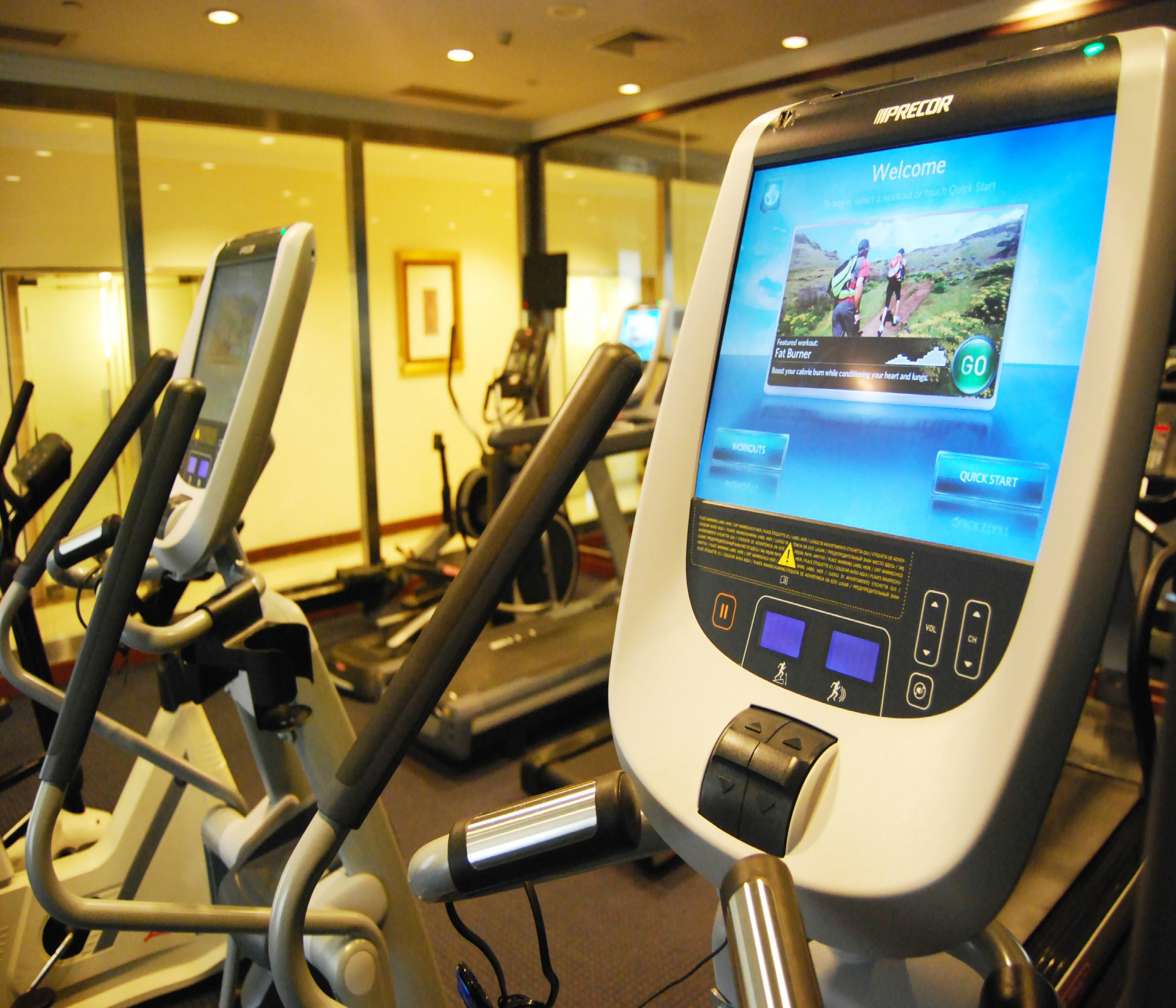 A treadmill with a digital screen displaying a workout video titled 'Welcome' and a 'Fat Burner' workout.
