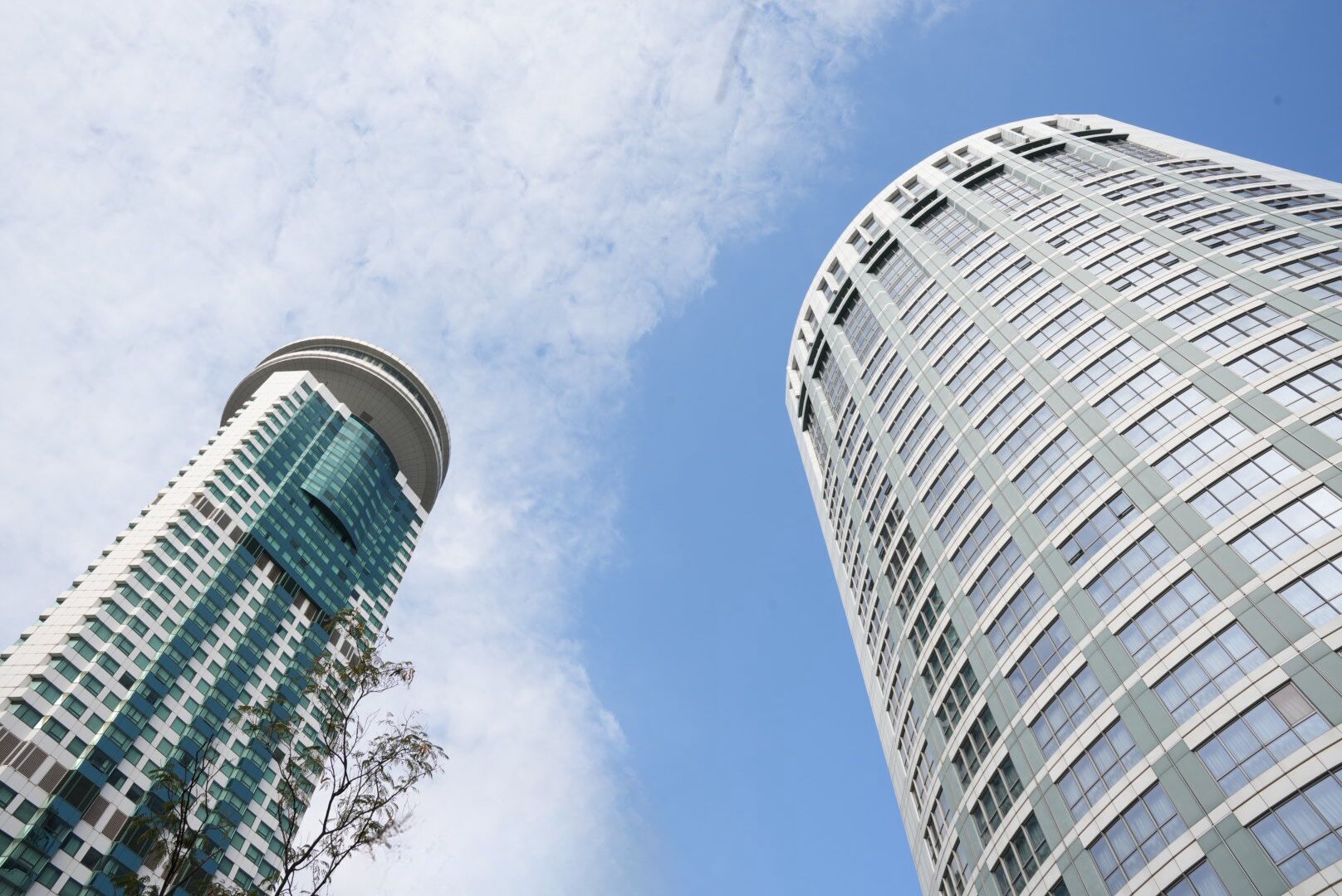 Two high-rise buildings with a clear sky and some clouds.