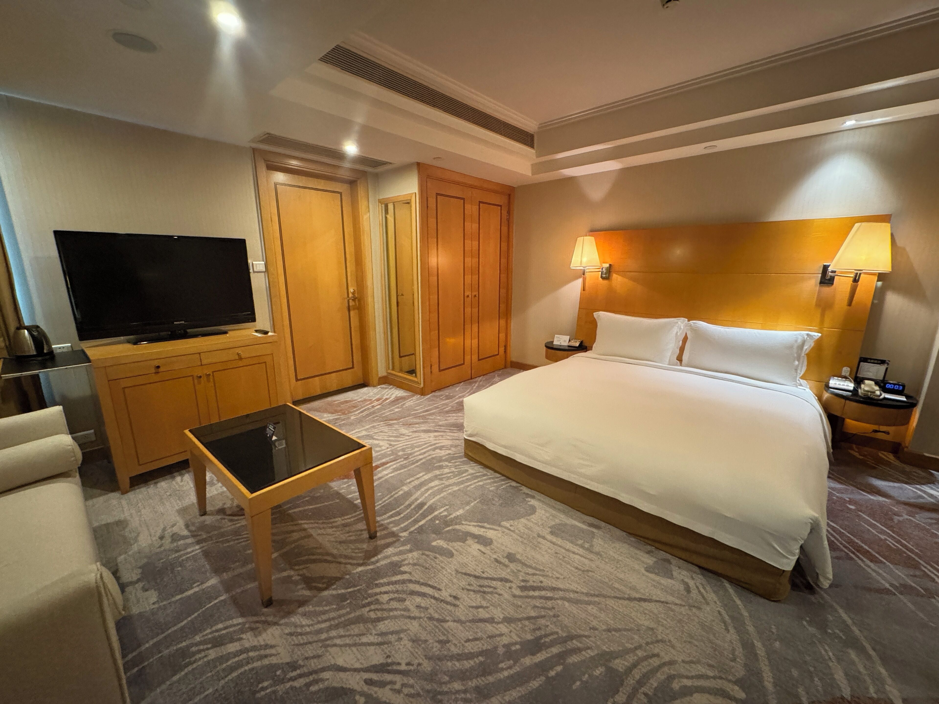 A hotel room with a bed, a TV, a desk, and a wardrobe.