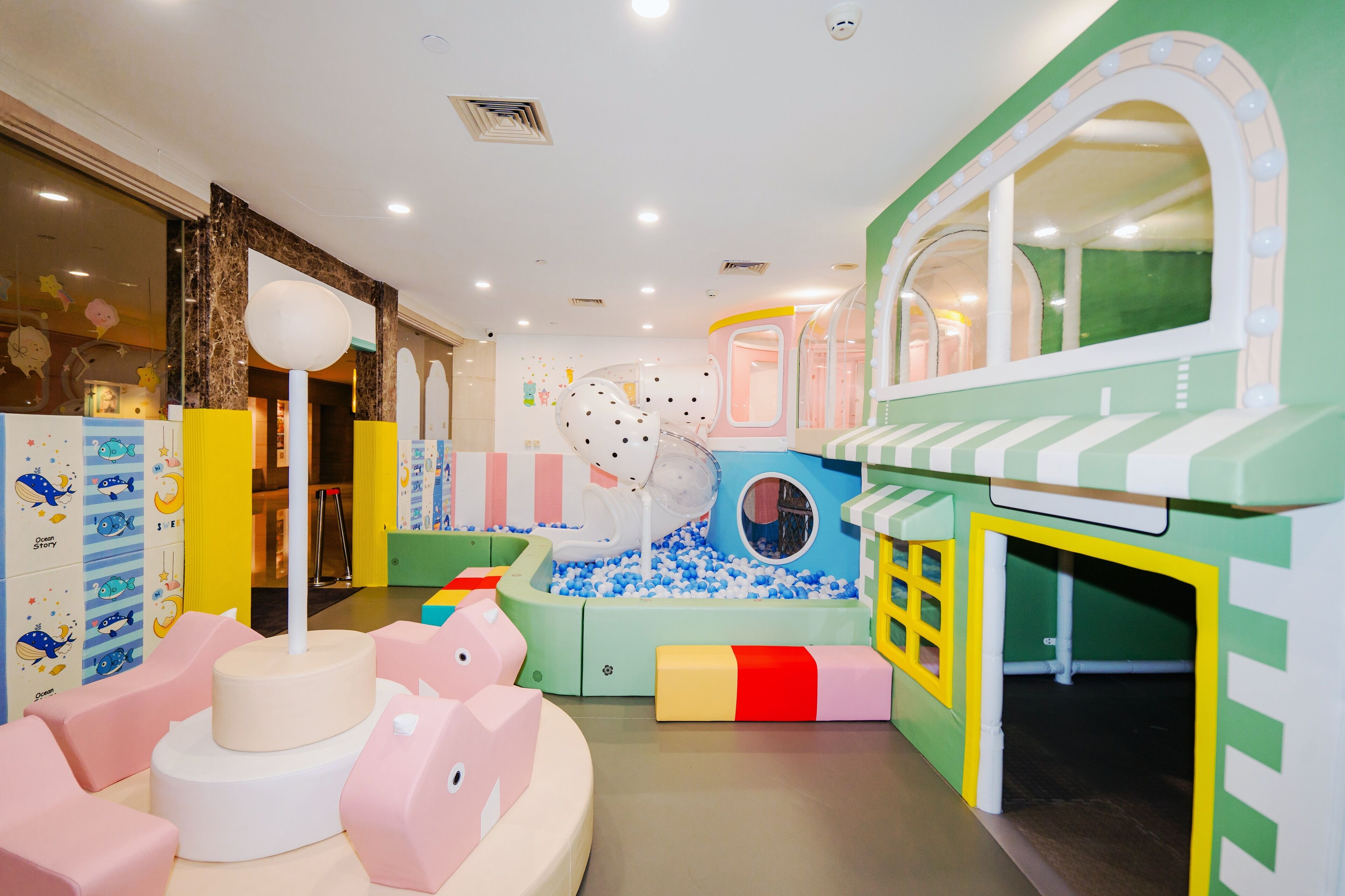 Ein Kinderspielbereich mit Bällebad, Rutsche und Spielhaus.