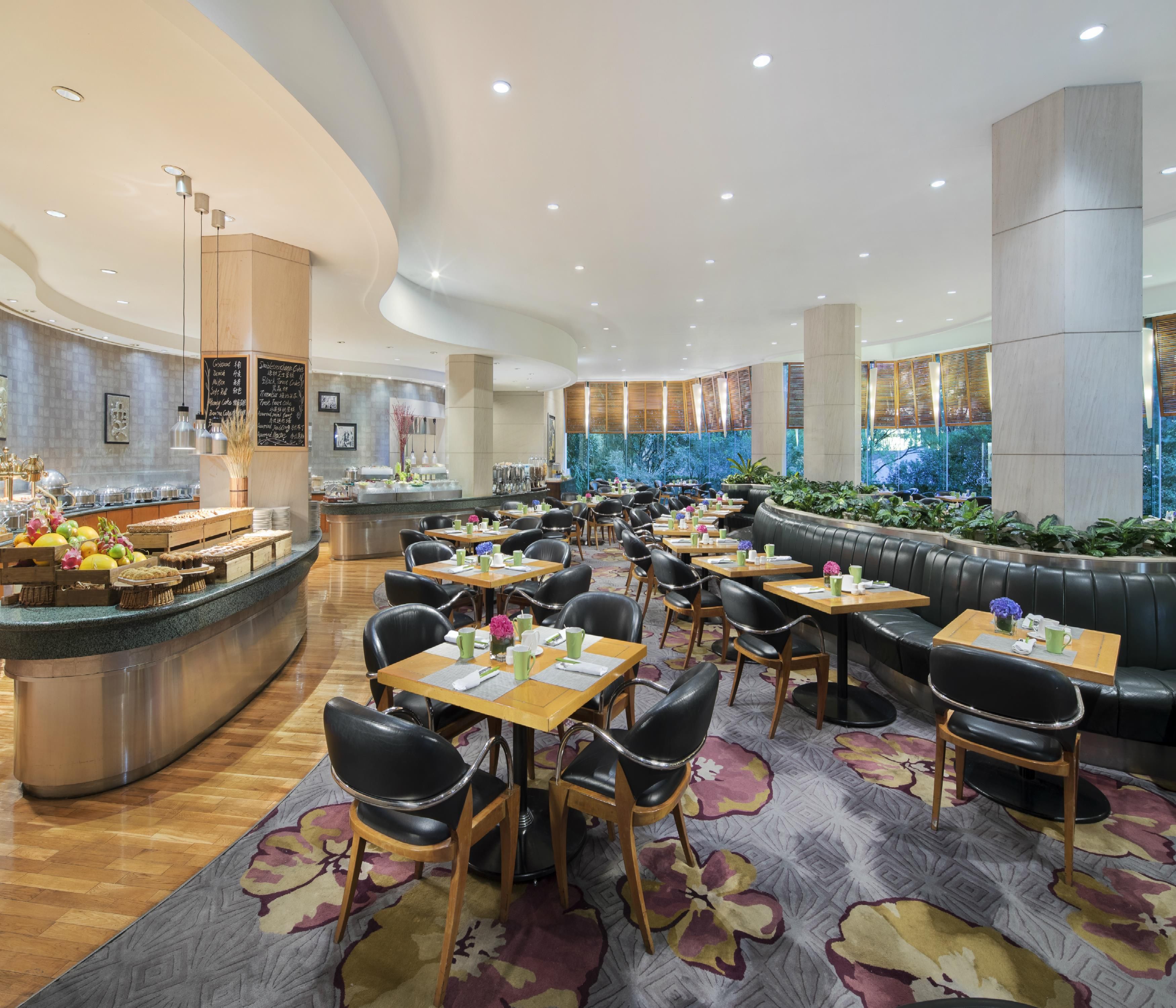 Un restaurant spacieux doté d’un plafond voûté, de plusieurs espaces de restauration comprenant des tables et un long banc, ainsi que d’un buffet proposant une variété de plats.