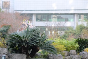 Een modern gebouw met grote ramen en een tuin vol planten en rotsen.