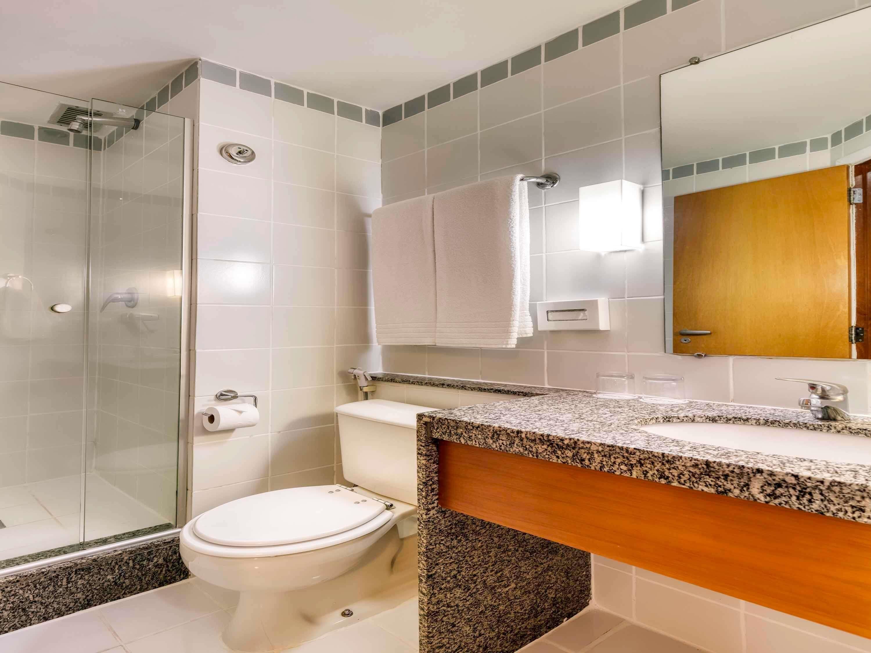 Une salle de bain avec une douche à parois de verre, des toilettes, un lavabo avec un plan de travail en granit et un meuble en bois.