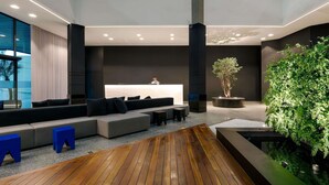 A modern lobby with a reception desk, seating area, and a wooden floor.
