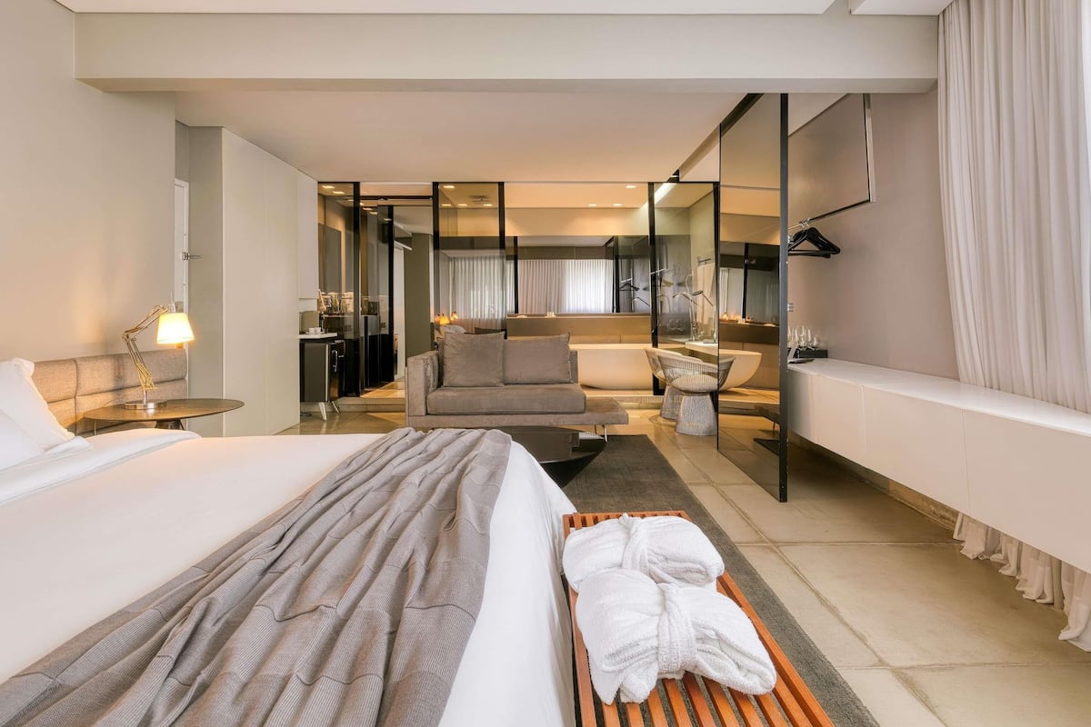 Une chambre d’hôtel moderne comprenant un lit, un coin salon, une salle de bain et une kitchenette.