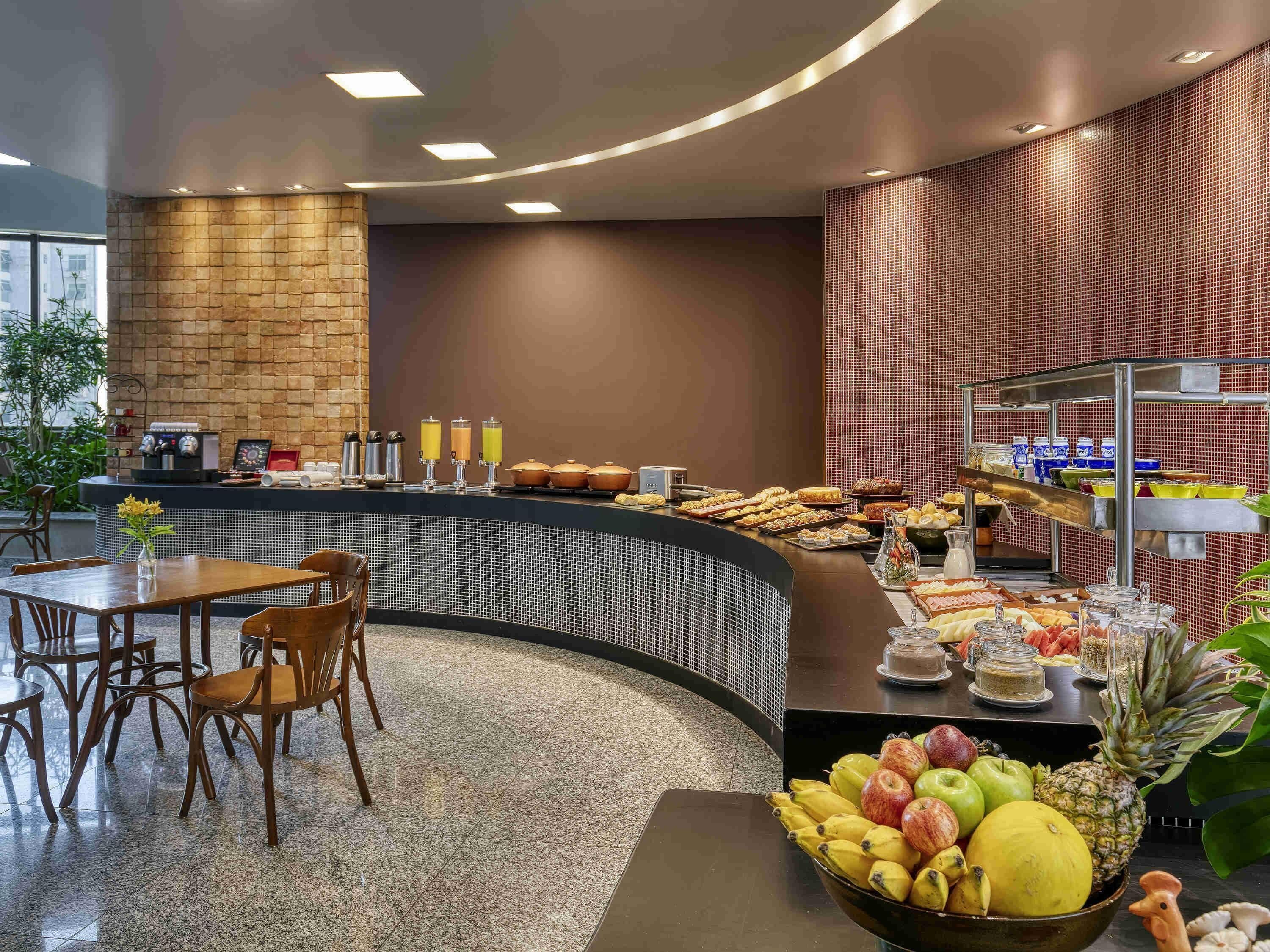 Ein Frühstücksbuffet mit verschiedenen Speisen, einer Kaffeestation und Sitzgelegenheiten.
