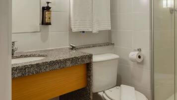 A bathroom with a granite countertop, a white toilet, a glass shower enclosure, and a towel rack.