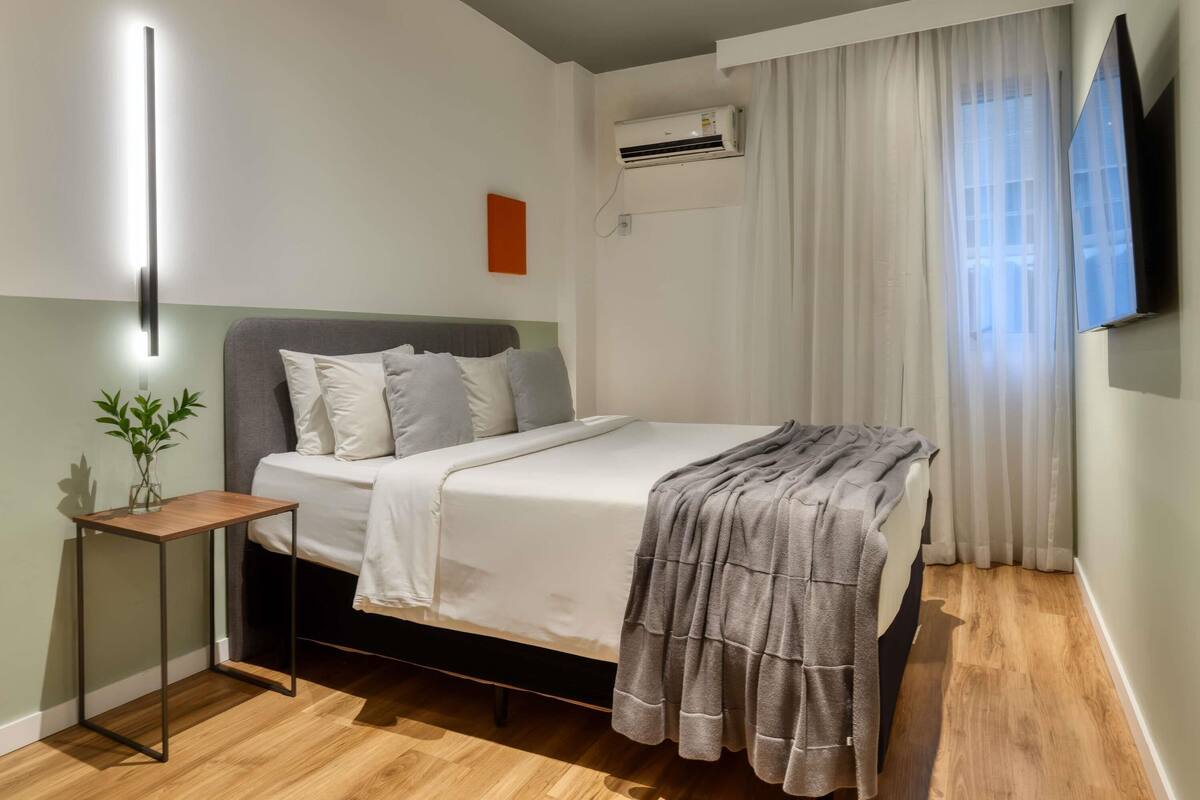 Une chambre moderne équipée d’un lit, d’une table de chevet, d’un climatiseur et d’un téléviseur.