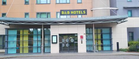 Un hotel con fachada moderna, amplias ventanas de vidrio y un cartel que dice "B&B HOTELS".