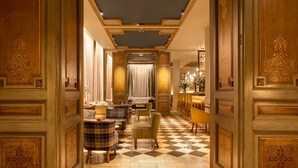Un vestíbulo de hotel con piso a cuadros, paneles de madera ornamentados y un área de descanso con varias sillas y mesas.