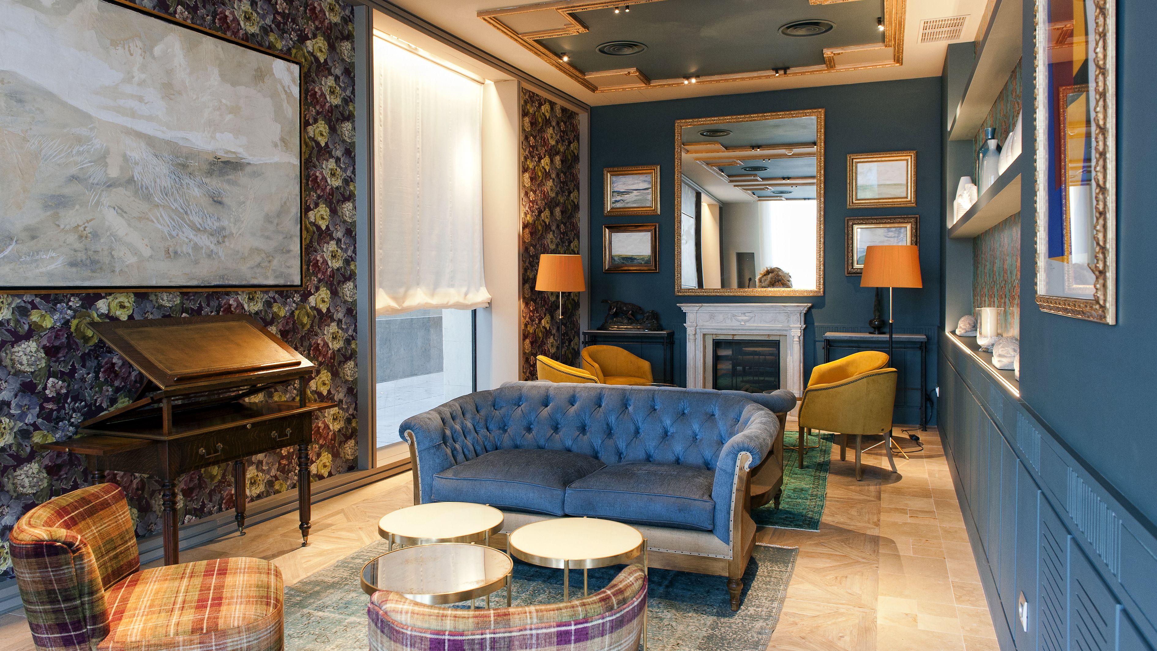 A room with a blue sofa, a piano, and a fireplace.