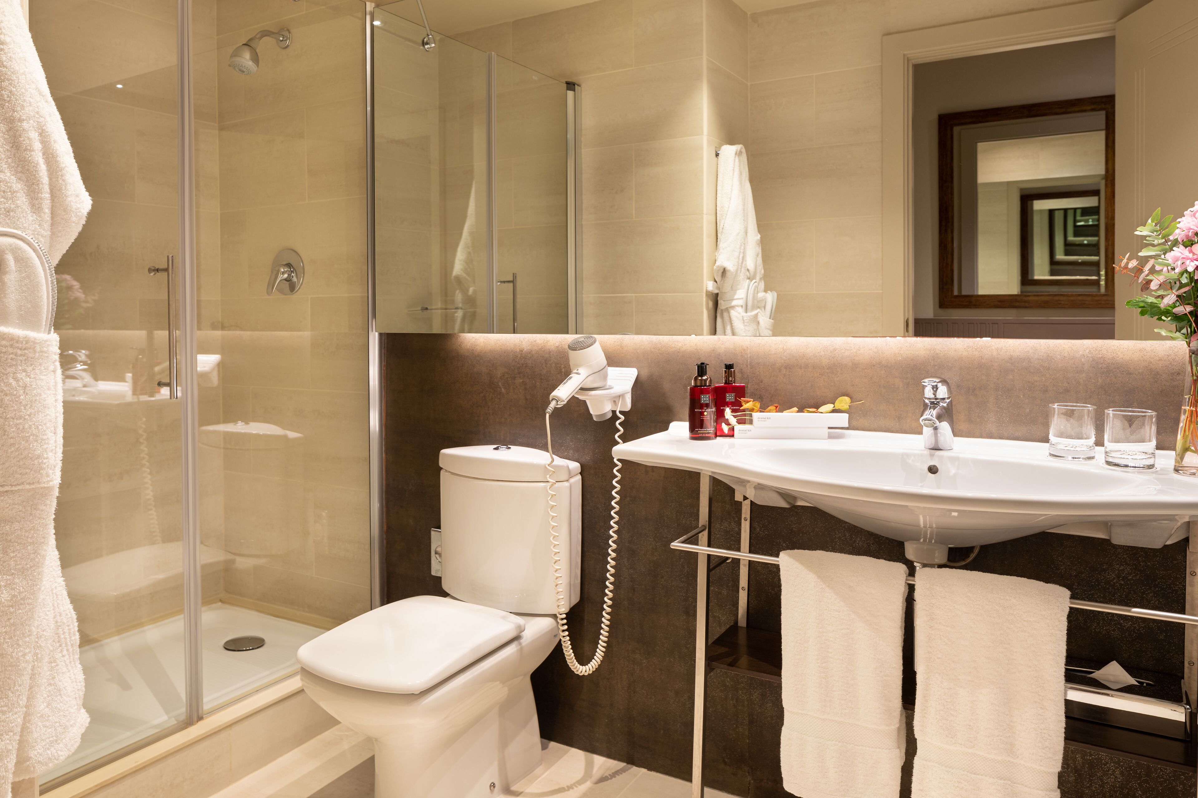 A modern bathroom with a glass-enclosed shower, a white toilet, a vanity with a sink, and a mirror.