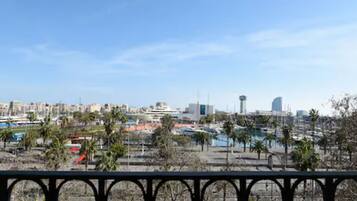 A coastal cityscape with modern buildings, a marina, and palm trees.