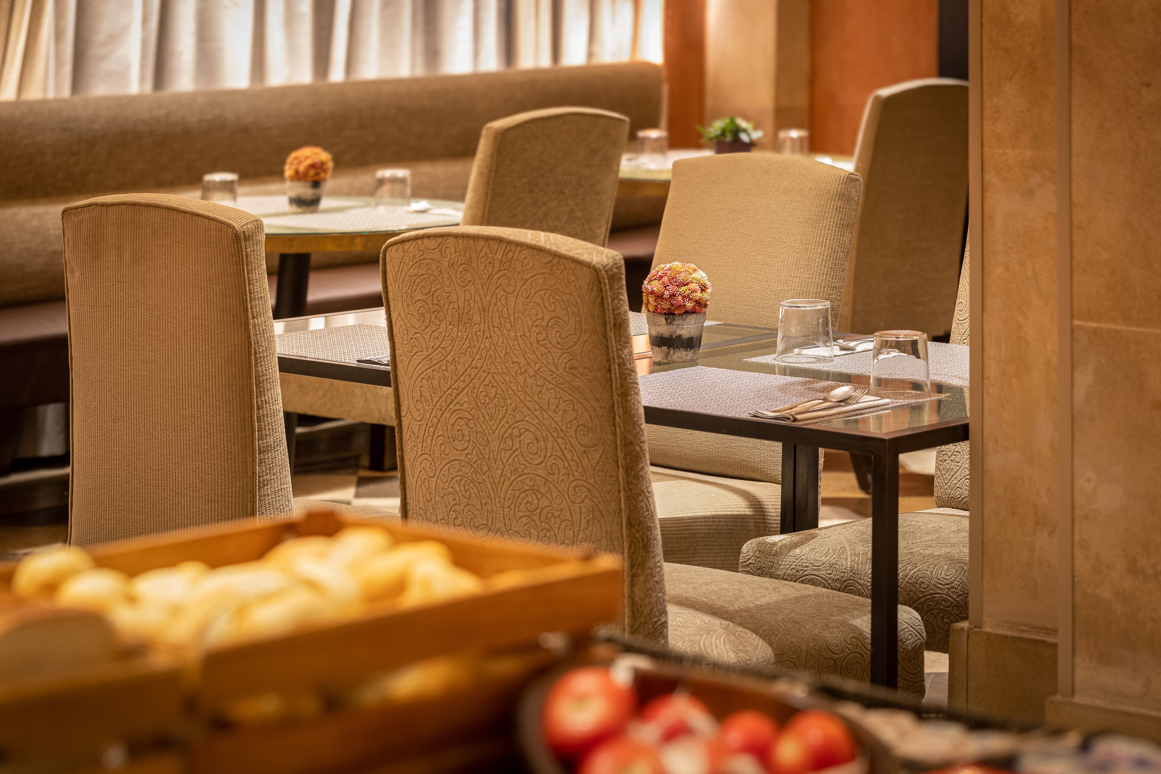 A dining area with a sofa, chairs, a table, and a fruit display.