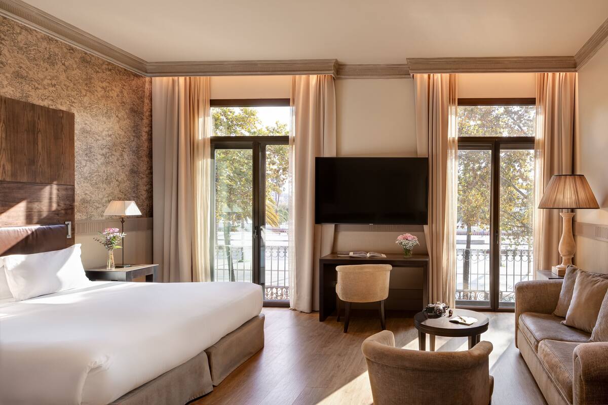 Ein Hotelzimmer mit einem großen Bett, einem Schreibtisch, einem Fernseher und einem Sofa.