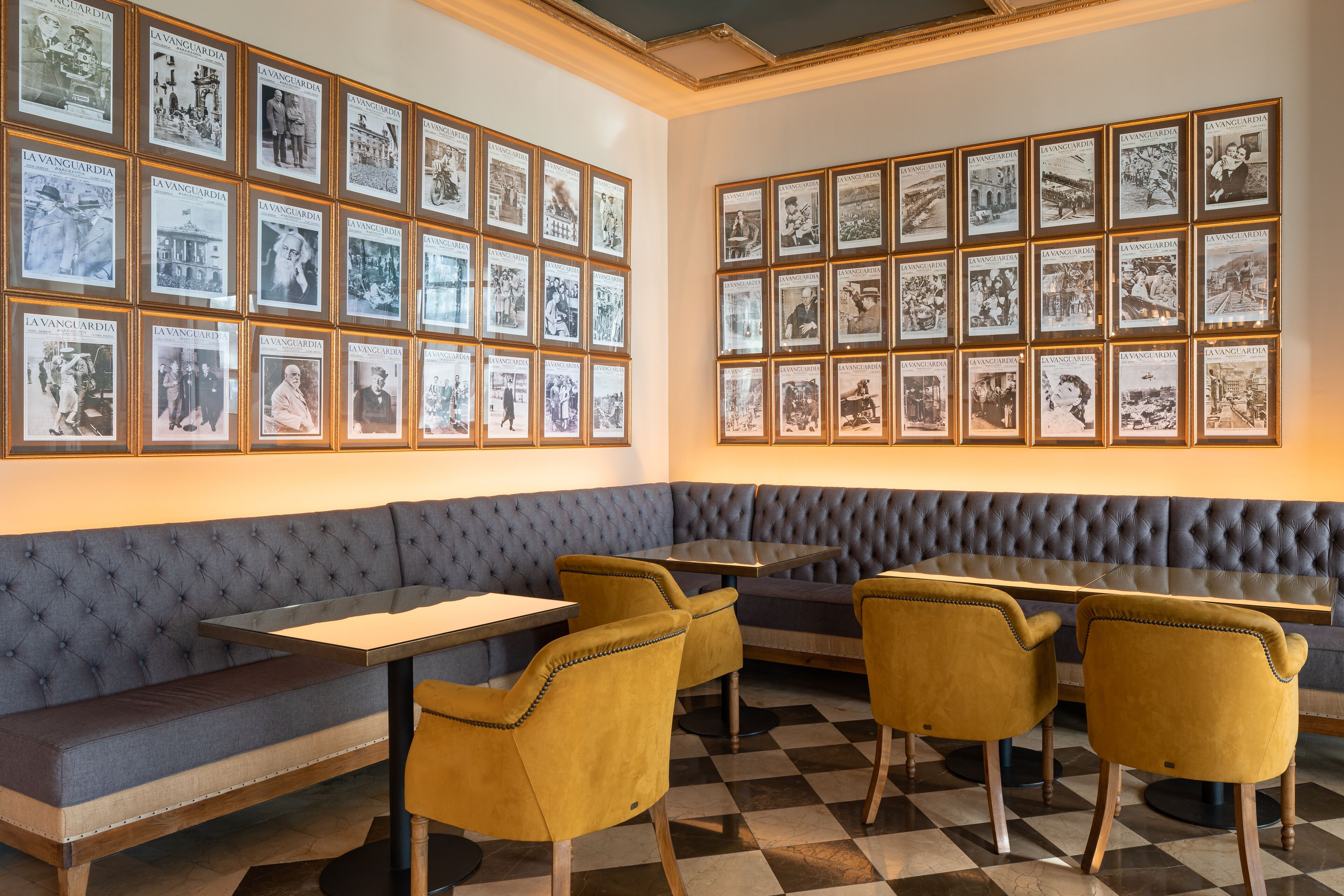 A restaurant with a checkered floor, a blue cushioned bench, and yellow chairs.