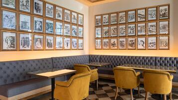 A restaurant with a checkered floor, a blue cushioned bench, and yellow chairs.