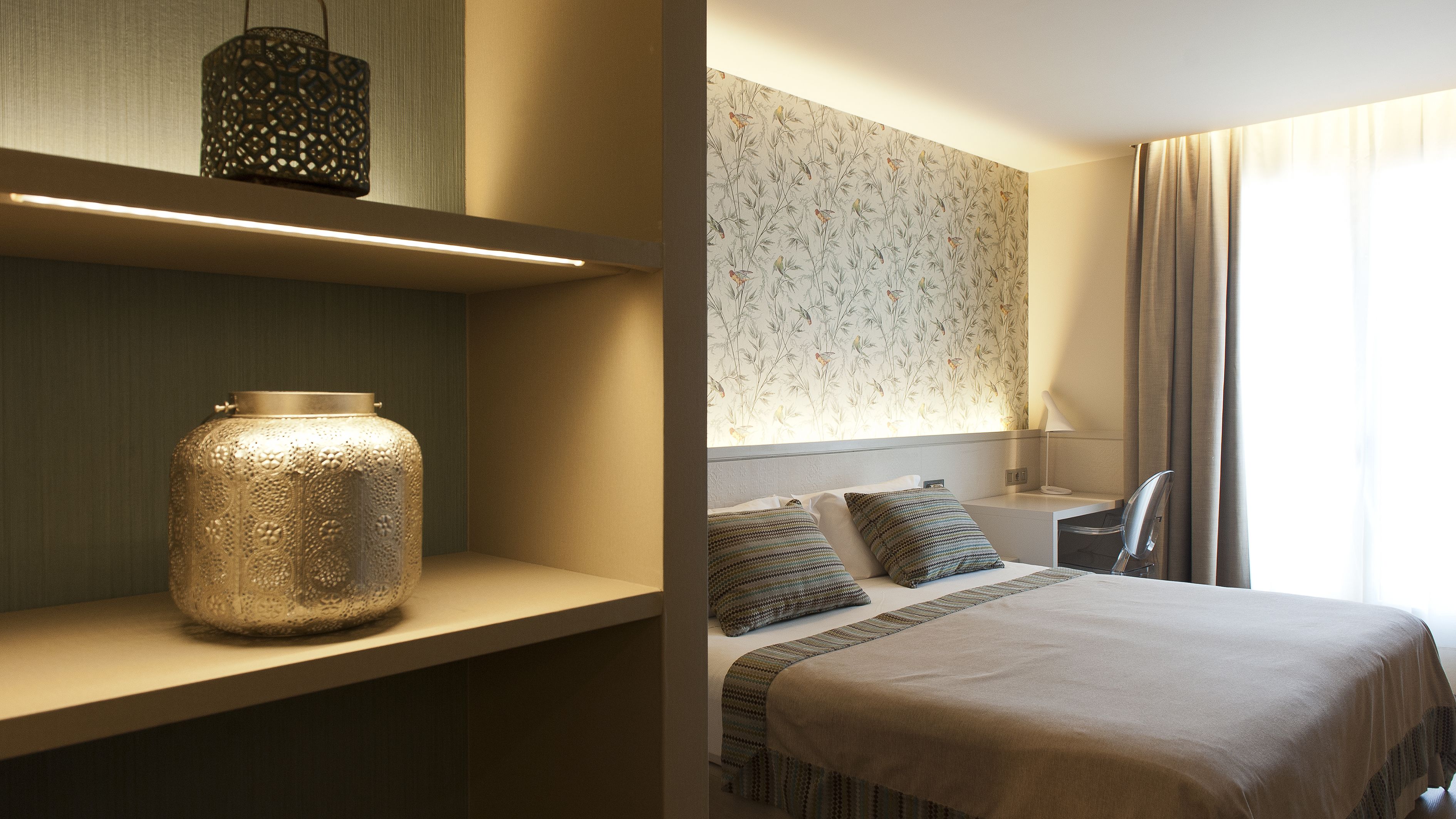 A hotel room with a large bed, a bedside table, a lamp, and a decorative vase.