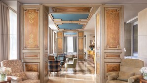 Un vestíbulo amplio con techos altos, paneles decorativos en las paredes y piso de diseño ajedrezado.