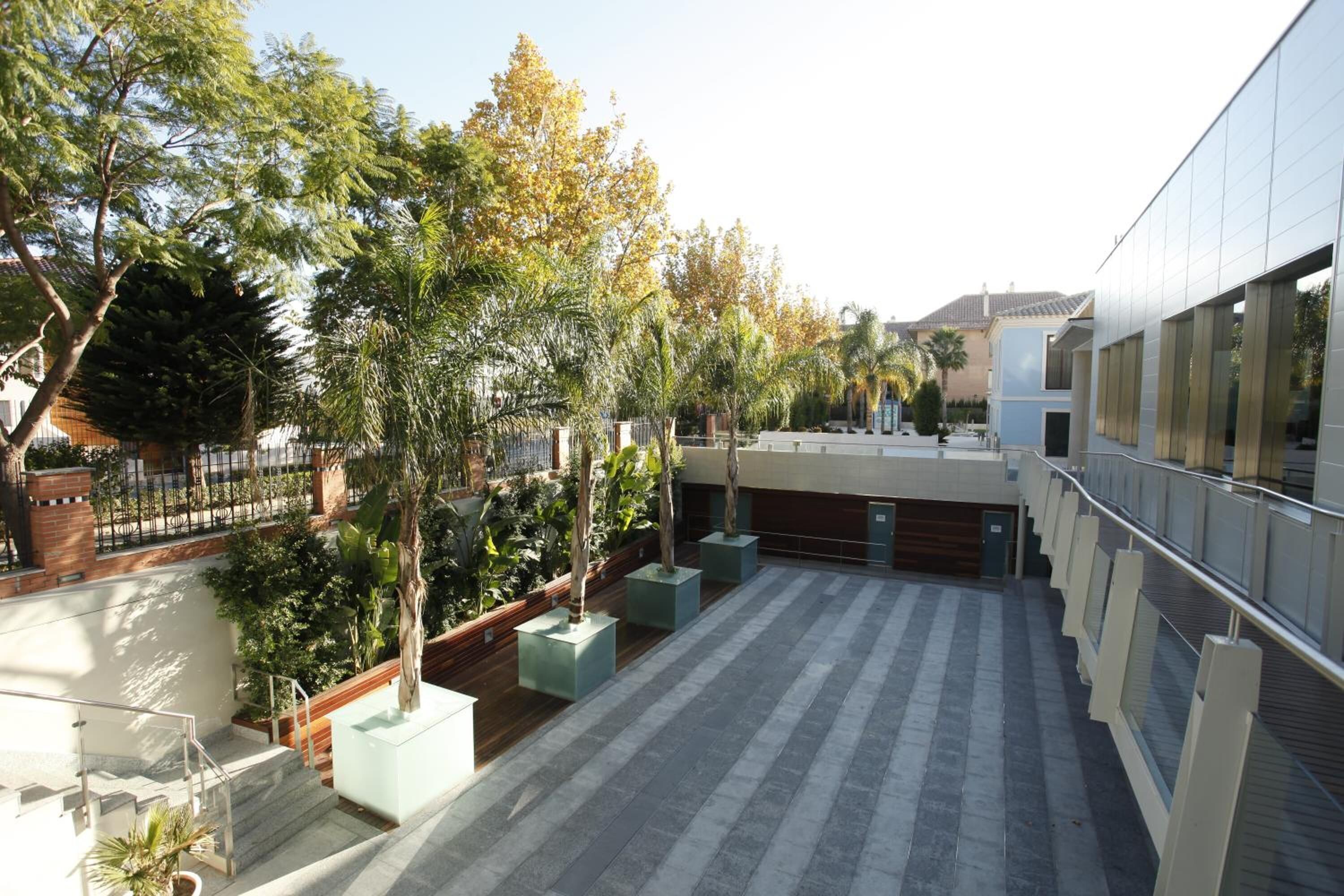 A courtyard with a modern building, potted plants, and a staircase.