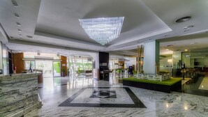 A spacious lobby with a marble floor, a large chandelier, and a reception desk.