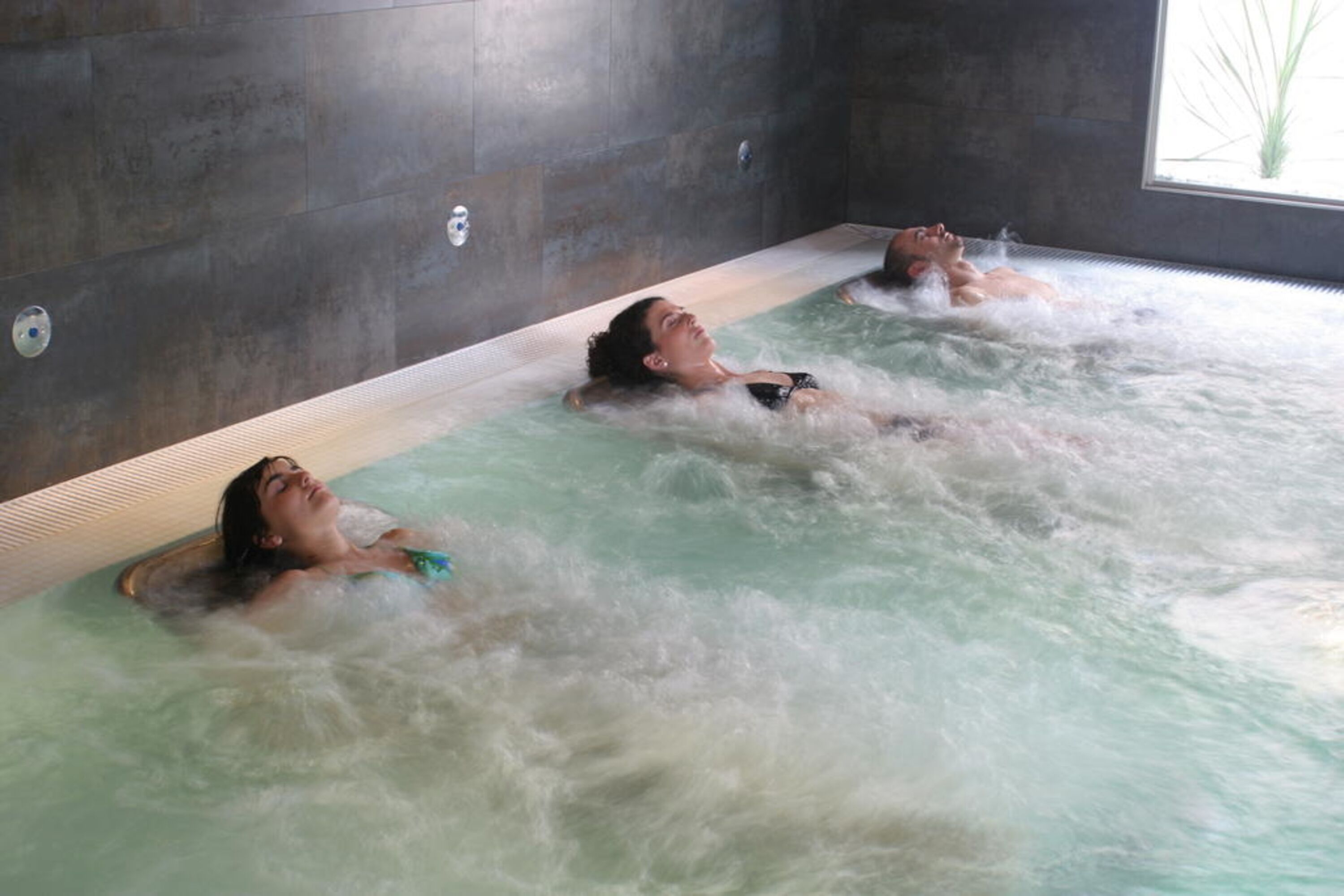 Et spaområde med tre personer, der slapper af i en jacuzzi.