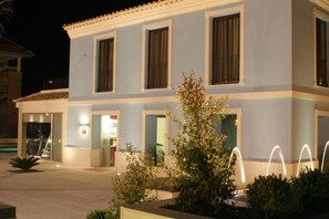A two-story building with a light blue facade, large windows, and a well-lit entrance. - Hotel Spa Jardines de Lorca (Lorca)